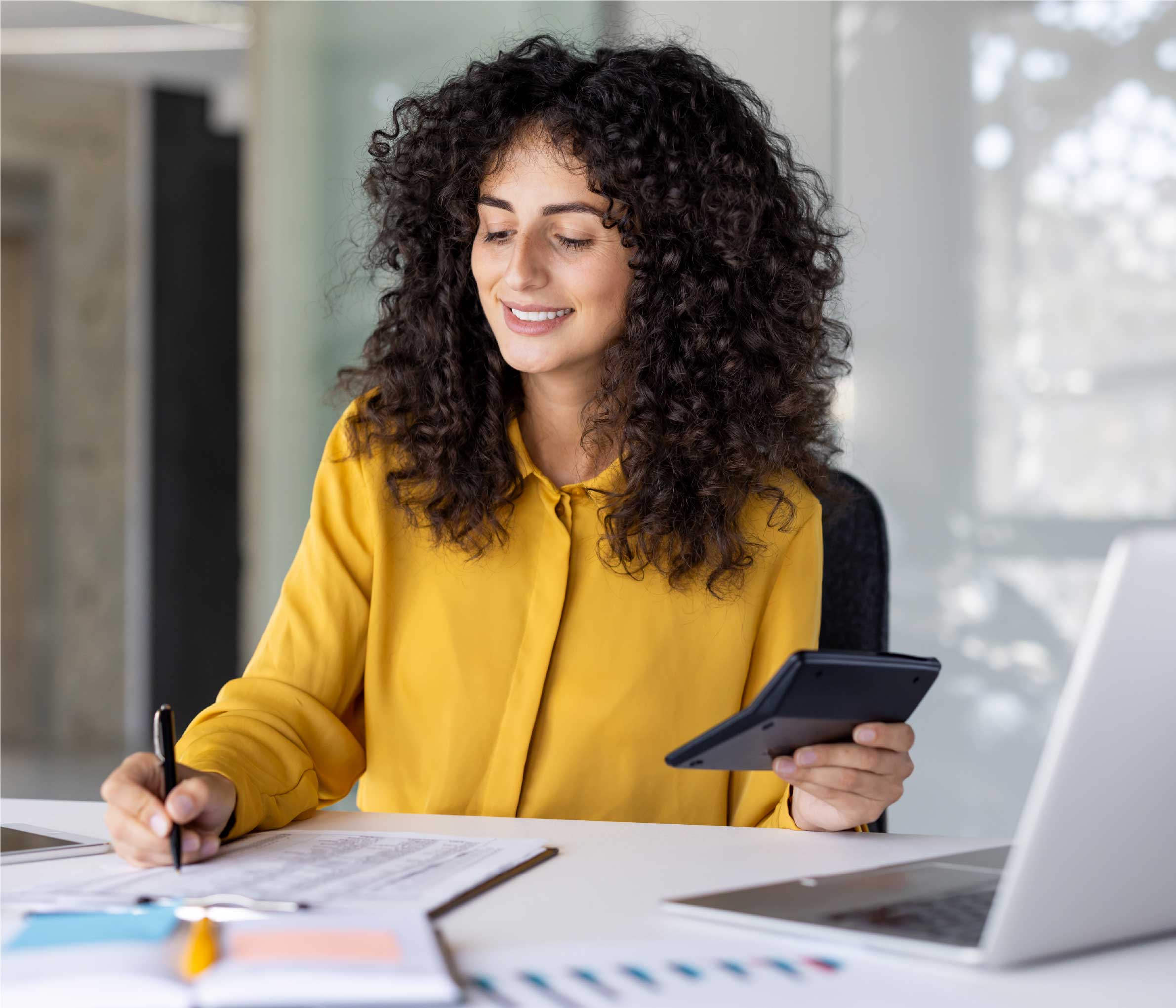 Une jeune fille écrit sur un bloc-notes d'une main et tient une calculatrice de l'autre.