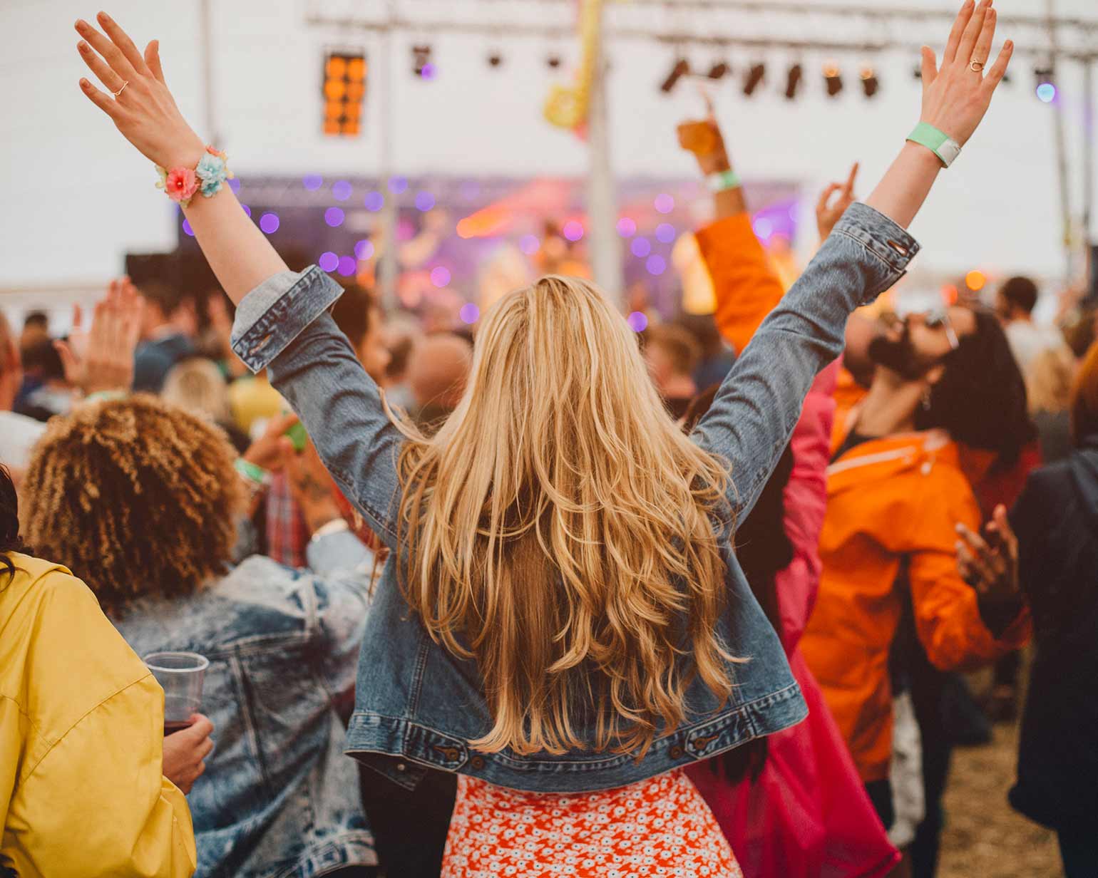 Une jeune femme regardant la scène, debout au milieu de la foule, pendant un festival de musique.