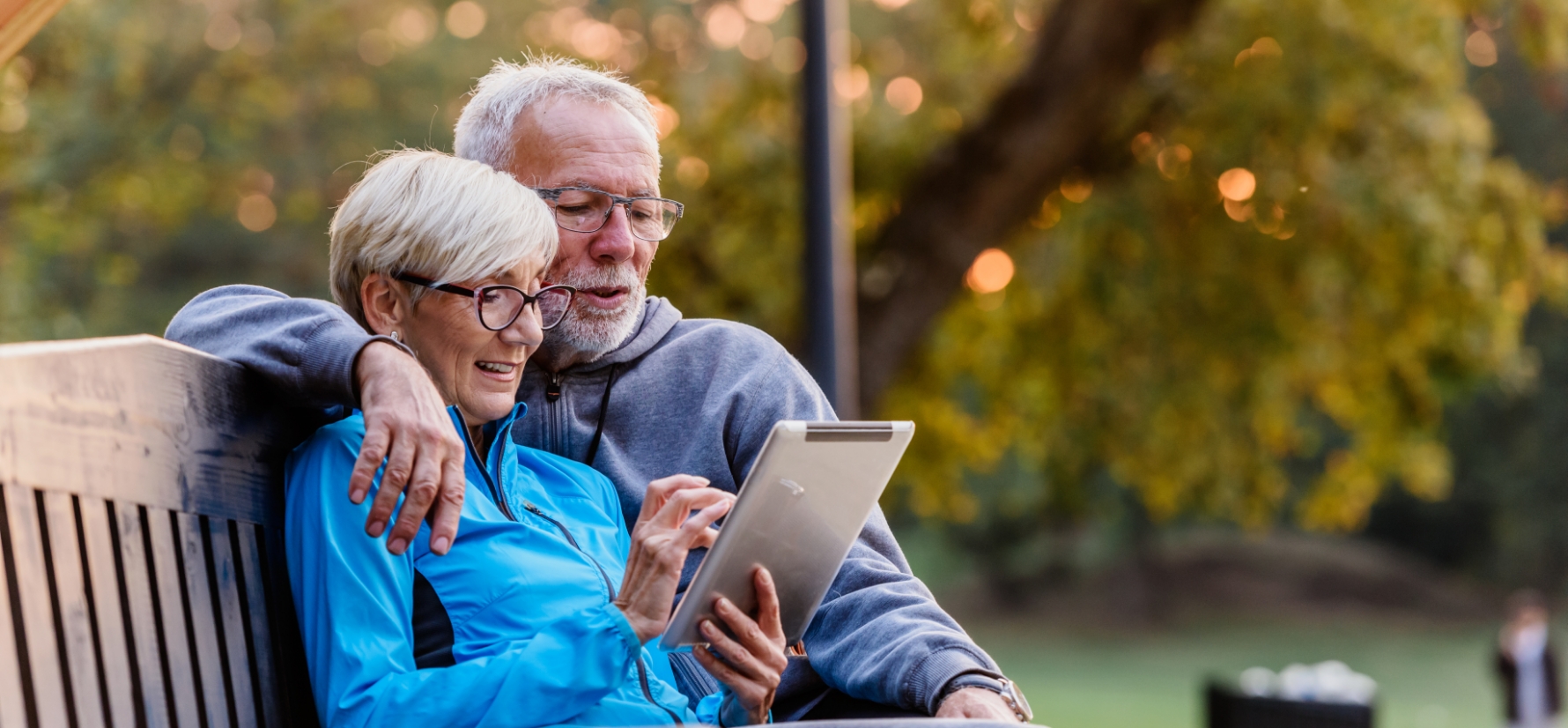 Un couple assis sur un banc, lisant sur un iPad.