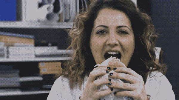 Une femme mord dans un hamburger.