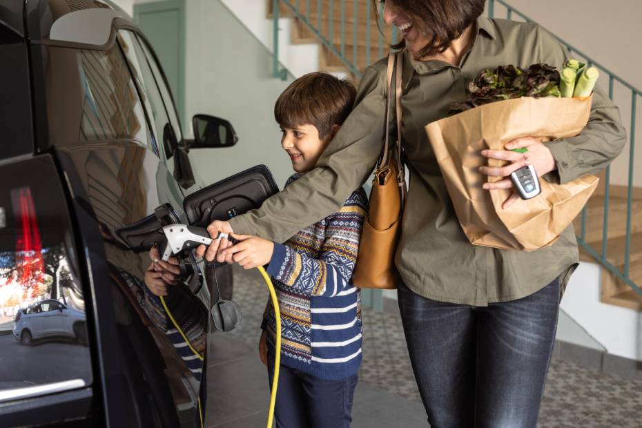 Un parent en compagnie d'un enfant recharge son véhicule électrique à domicile.