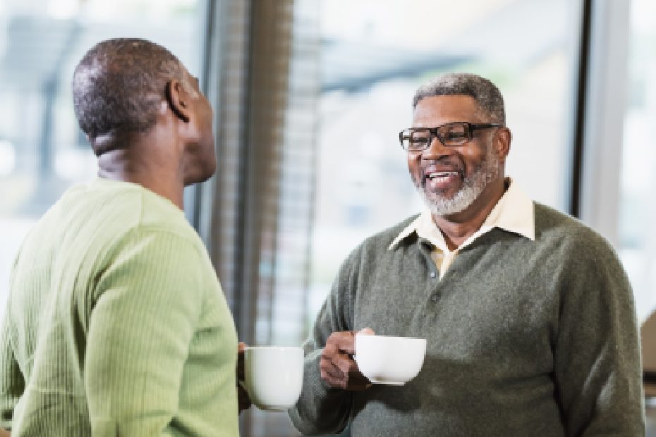Image de deux hommes en train de discuter en prenant un café