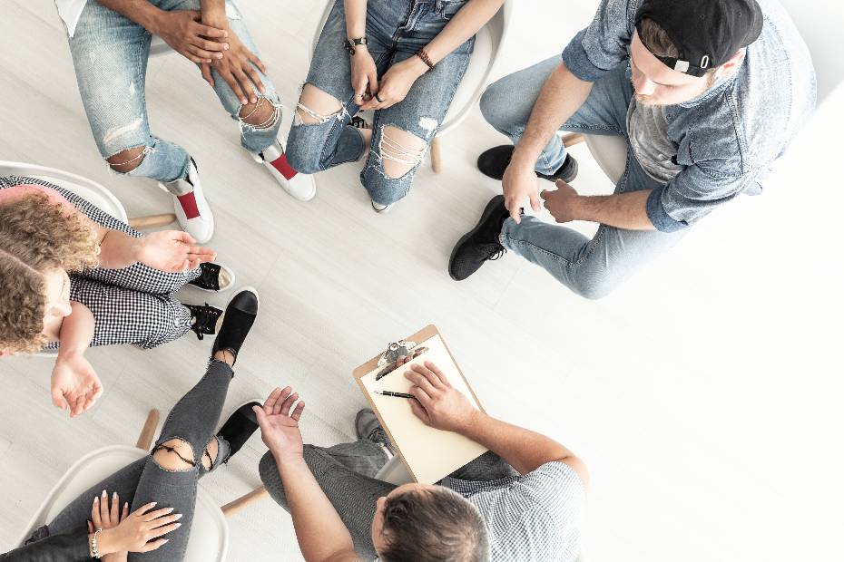 Vue de dessus d'un psychothérapeute travaillant avec un groupe d'adolescents difficiles dans une classe de gestion de la colère