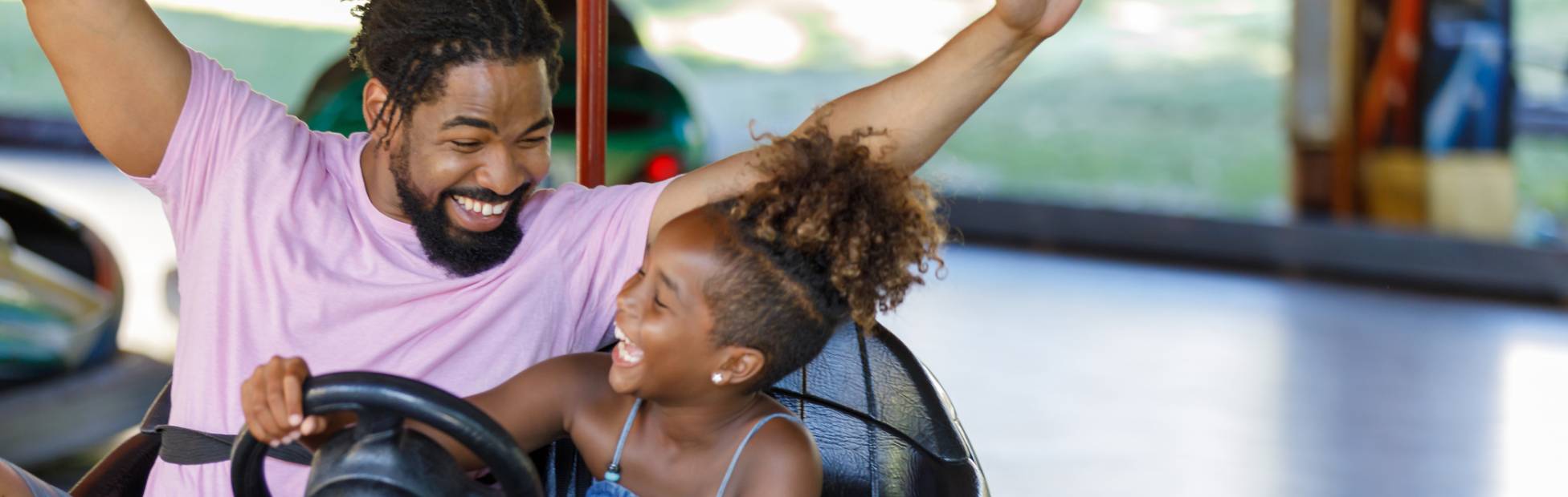 Un jeune père et sa fille s'amusent à bord d'une auto tamponneuse dans un parc d'attractions
