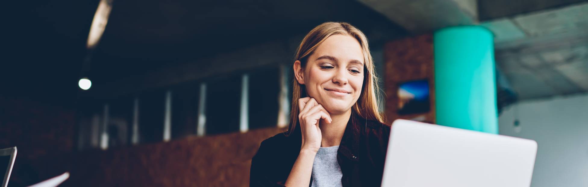 Femme souriant à l'écran d'un ordinateur portable