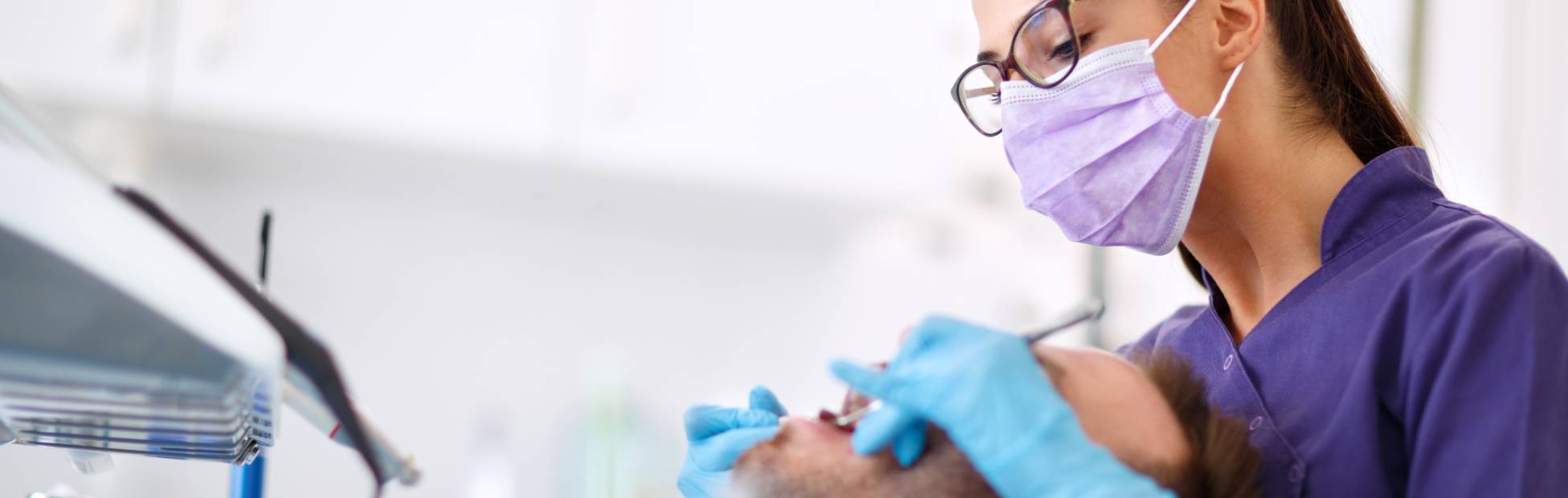 Une jeune dentiste examine les dents d'un patient dans une clinique