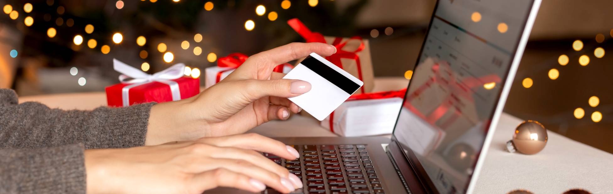 les mains d'une femme tenant une carte de crédit, faisant du shopping sur un ordinateur portable.