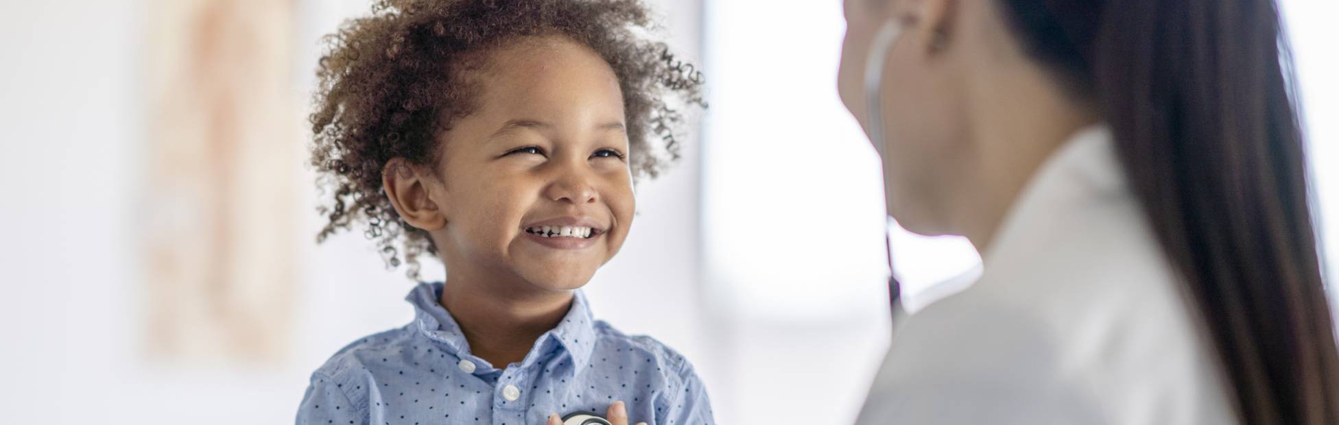 Une médecin ausculte le cœur d'un petit garçon.