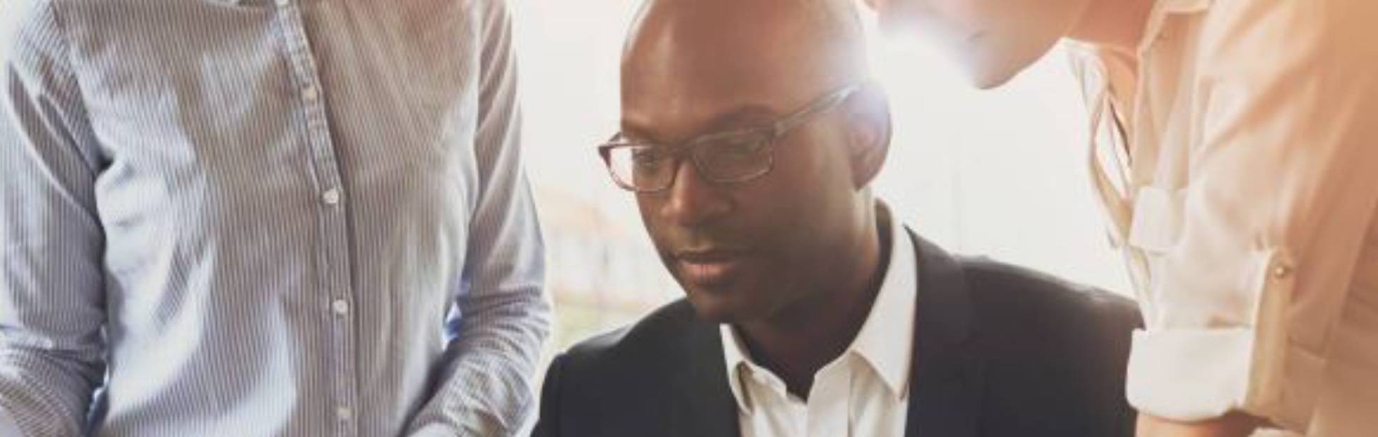 Homme et collègues regardant un écran d'ordinateur portable