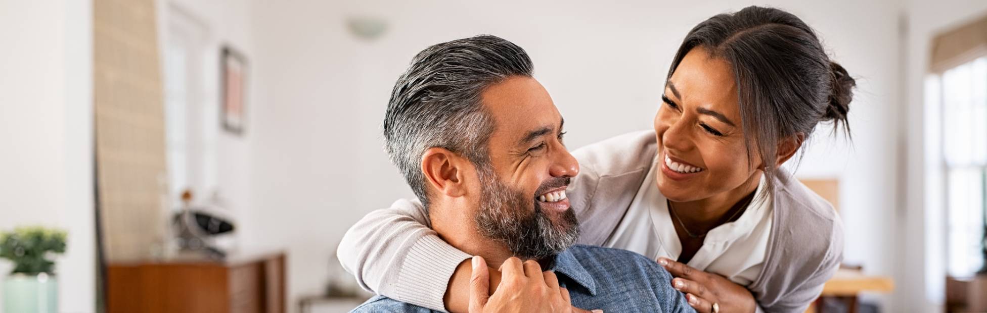 Image d'une femme placée derrière son conjoint qu'elle entoure de ses bras.