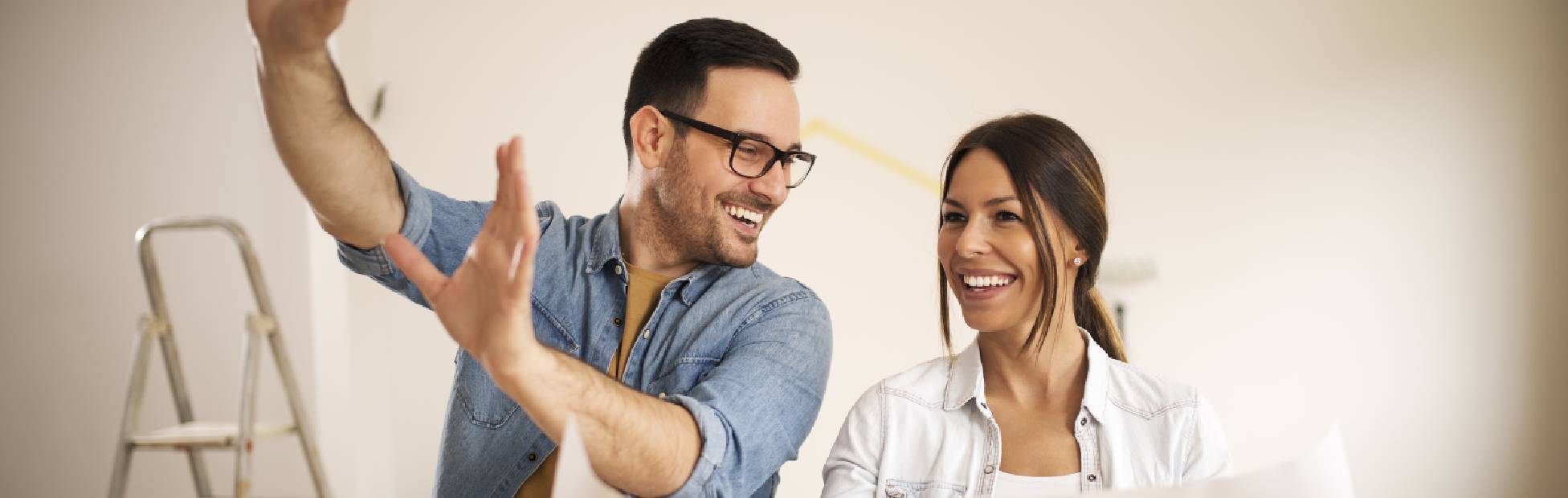 Un couple heureux qui regarde un plan directeur prévoit de rénover sa maison et d'ajouter de la valeur
