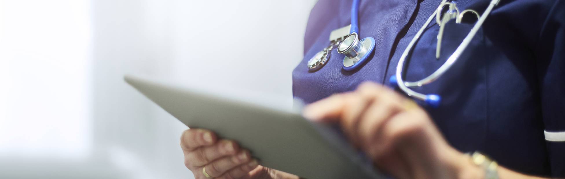 Une infirmière consulte les dossiers des patients sur sa tablette numérique.