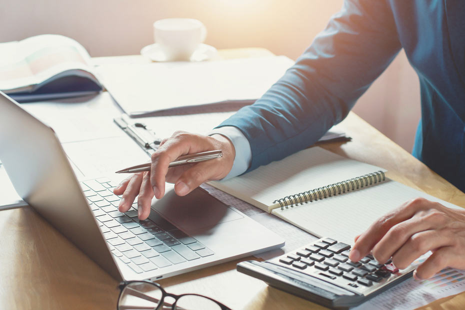 Une image montrant un homme utilisant une calculatrice et un ordinateur portable.