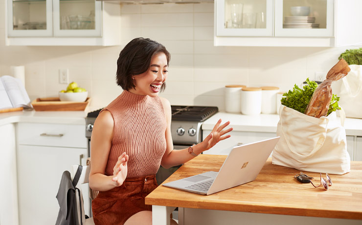 Dame dans la cuisine travaillant sur son ordinateur portable