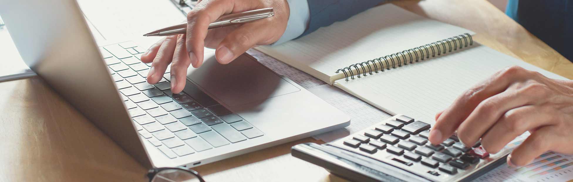 Une image montrant un homme utilisant une calculatrice et un ordinateur portable.