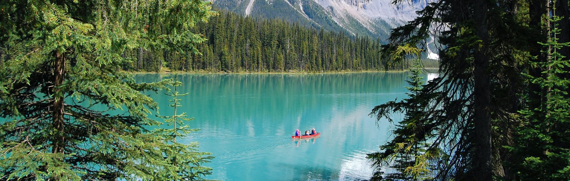 La nature, les montagnes et un canoë orange au milieu.