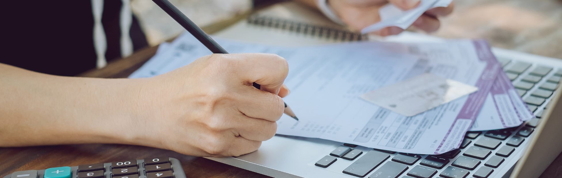 Femme à un bureau qui gère des factures à l'aide d'une calculatrice