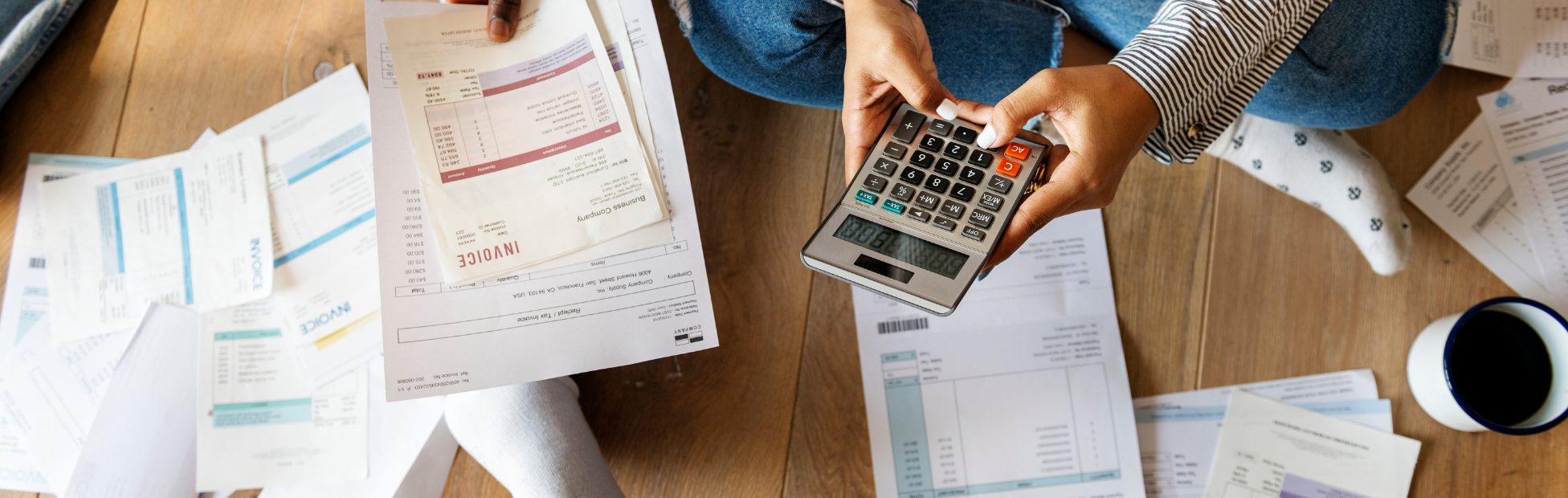 Gros plan de deux personnes assises par terre avec une calculatrice et des factures