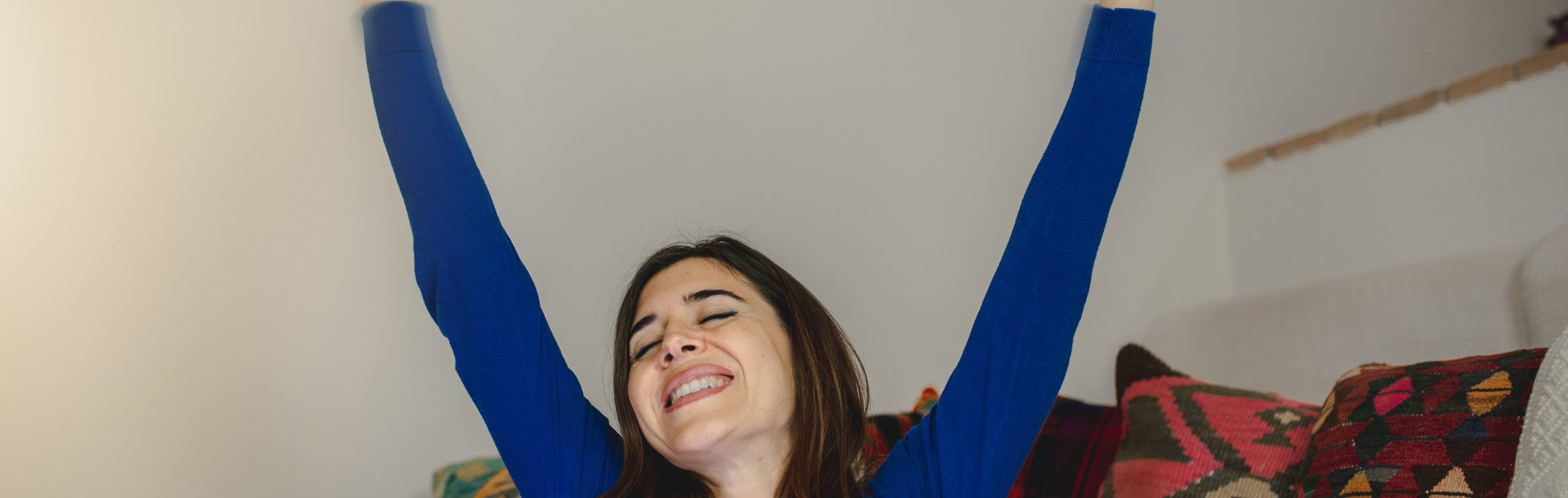 Femme levant joyeusement les bras en l'air, cartes de crédit en main