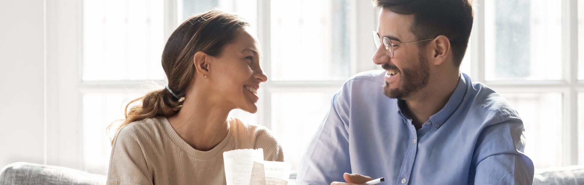 Un couple souriant sur un canapé, travaillant à un budget