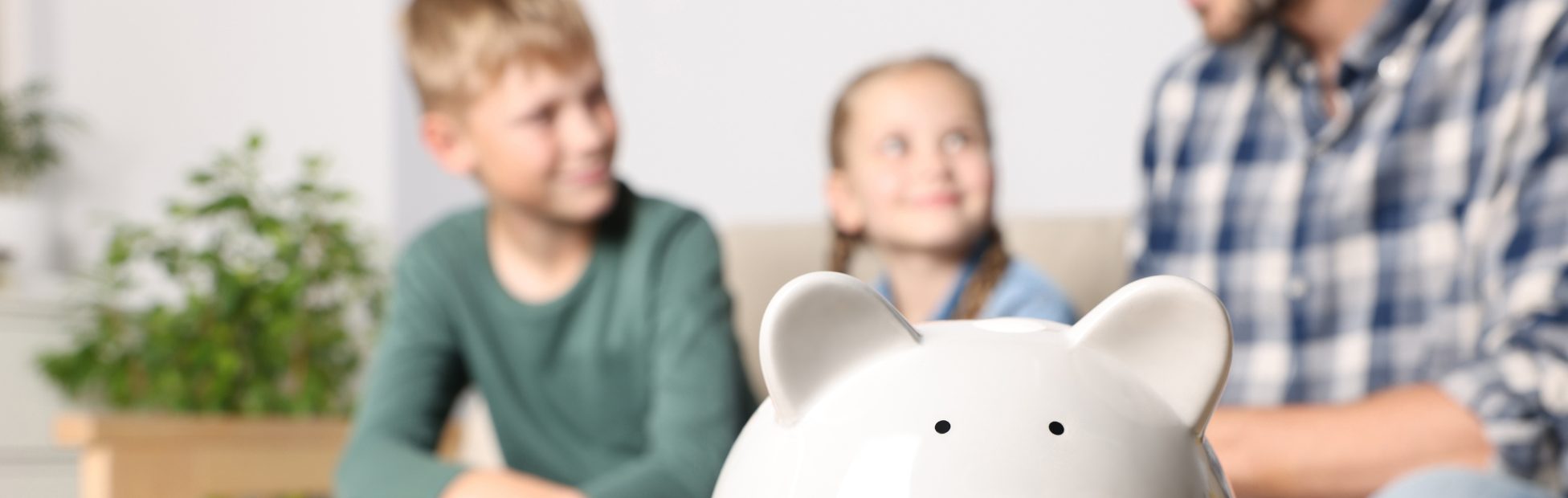Un père avec son fils et sa fille, avec une tirelire au premier plan