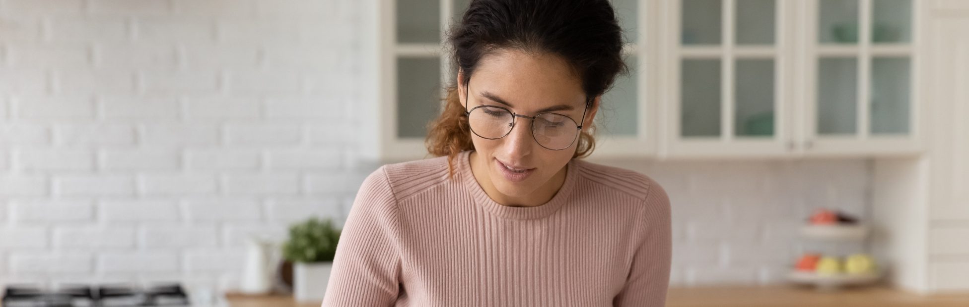 Une femme confiante portant des lunettes compte des factures et calcule son budget à la maison