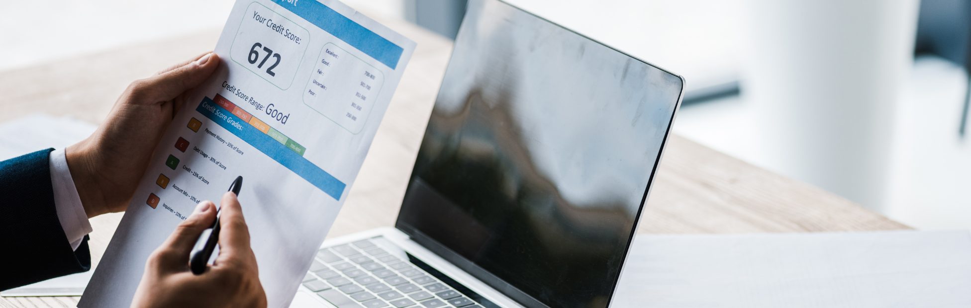 Un homme ayant une copie imprimée de son rapport de solvabilité examine ses finances en ligne