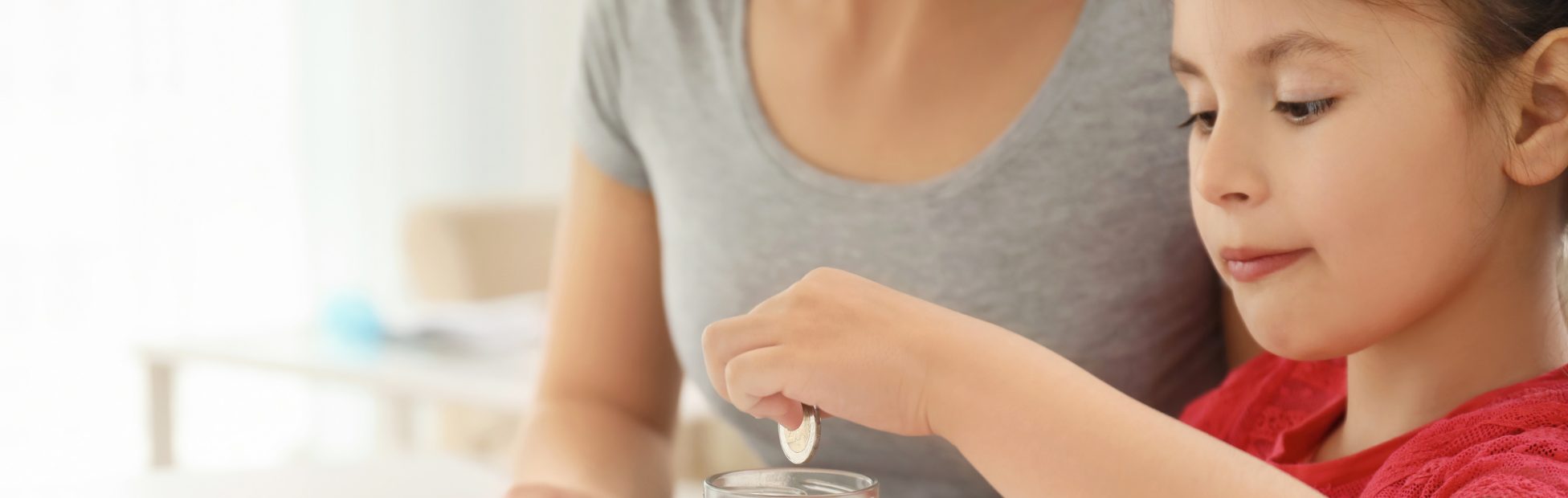 Jeune fille et sa mère qui comptent de l'argent à une table.