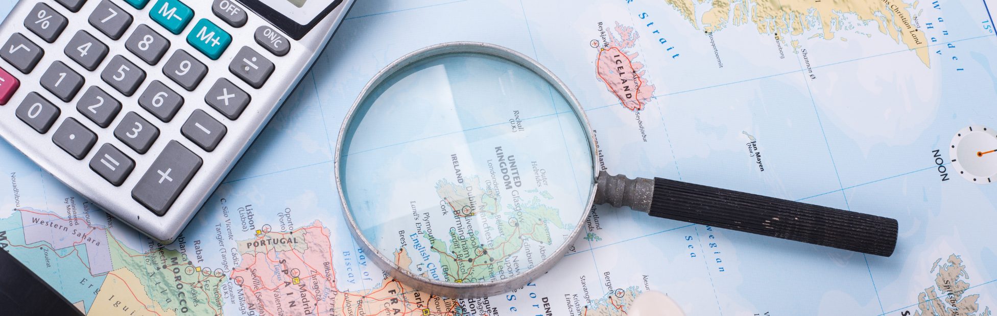 Carte du monde avec loupe, tirelire et calculatrice