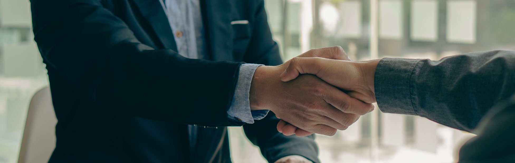 Poignée de main entre deux hommes au-dessus de documents et d'un maillet sur un bureau.