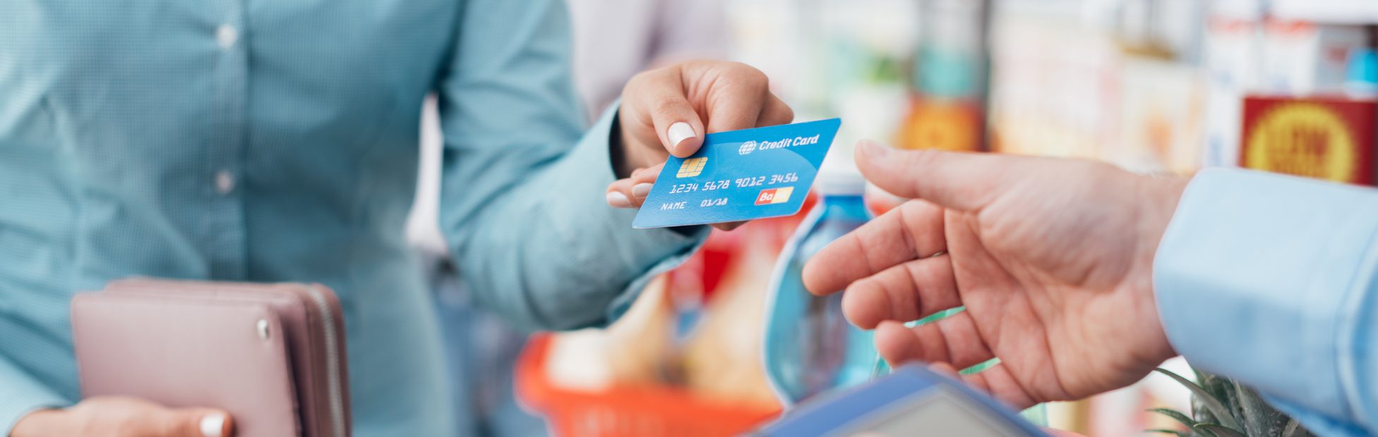 Femme dans une épicerie, payant avec sa carte de crédit