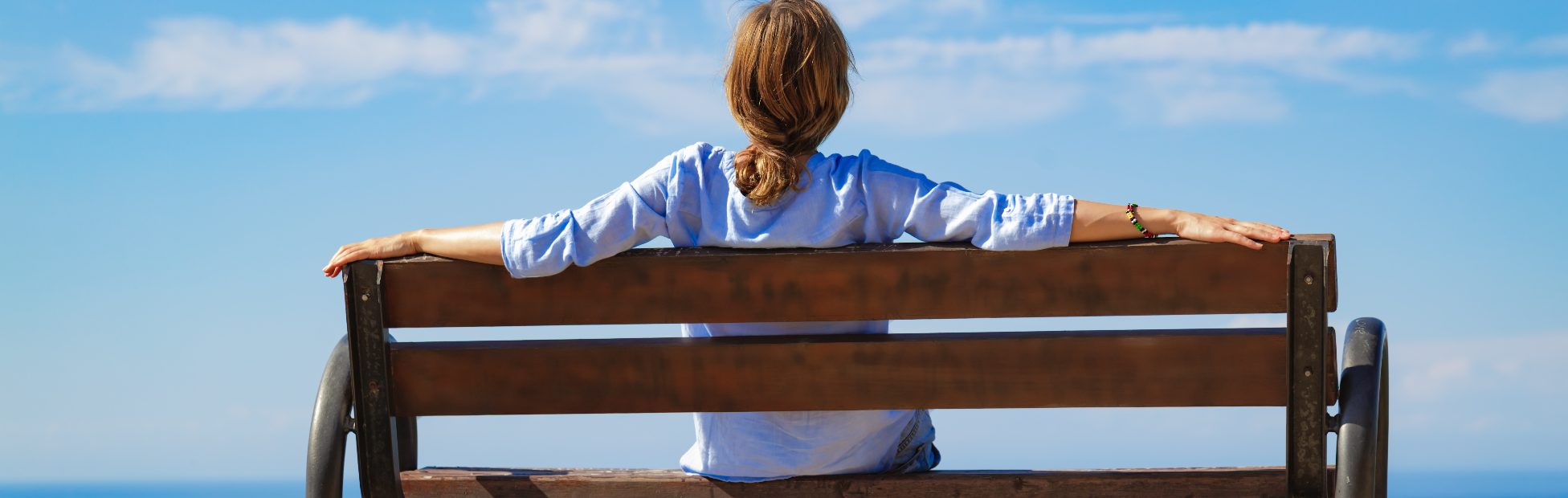 Femme assise sur un banc avec vue sur l'océan