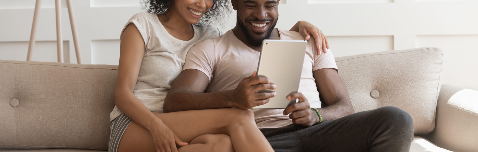 Un couple assis sur le canapé avec une tablette